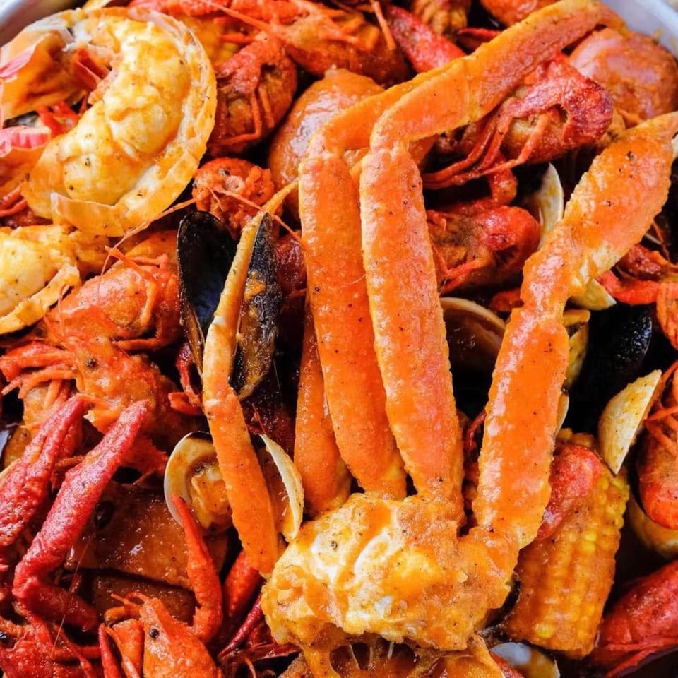 Close-up of a seafood boil with crab legs, crawfish, mussels, clams, and corn on the cob.
