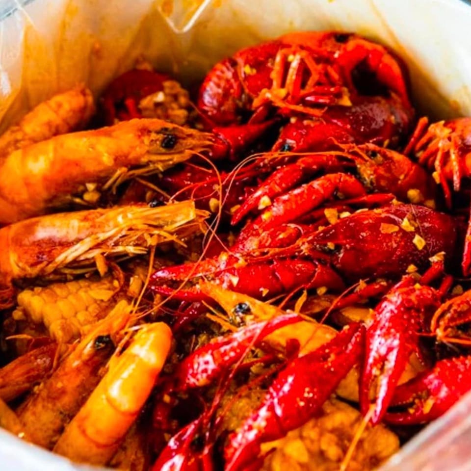 Boiled crawfish and shrimp with corn on the cob, seasoned with garlic and spices.